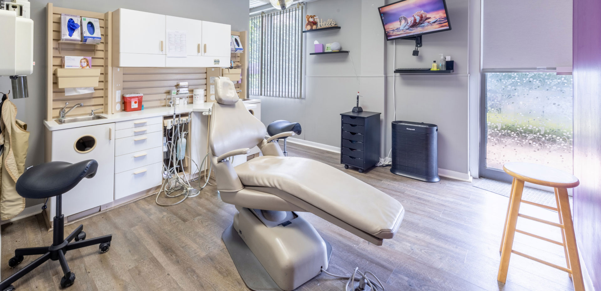 exam room with cabinets, dental chair and equipment, and computers monitor mounted on wall