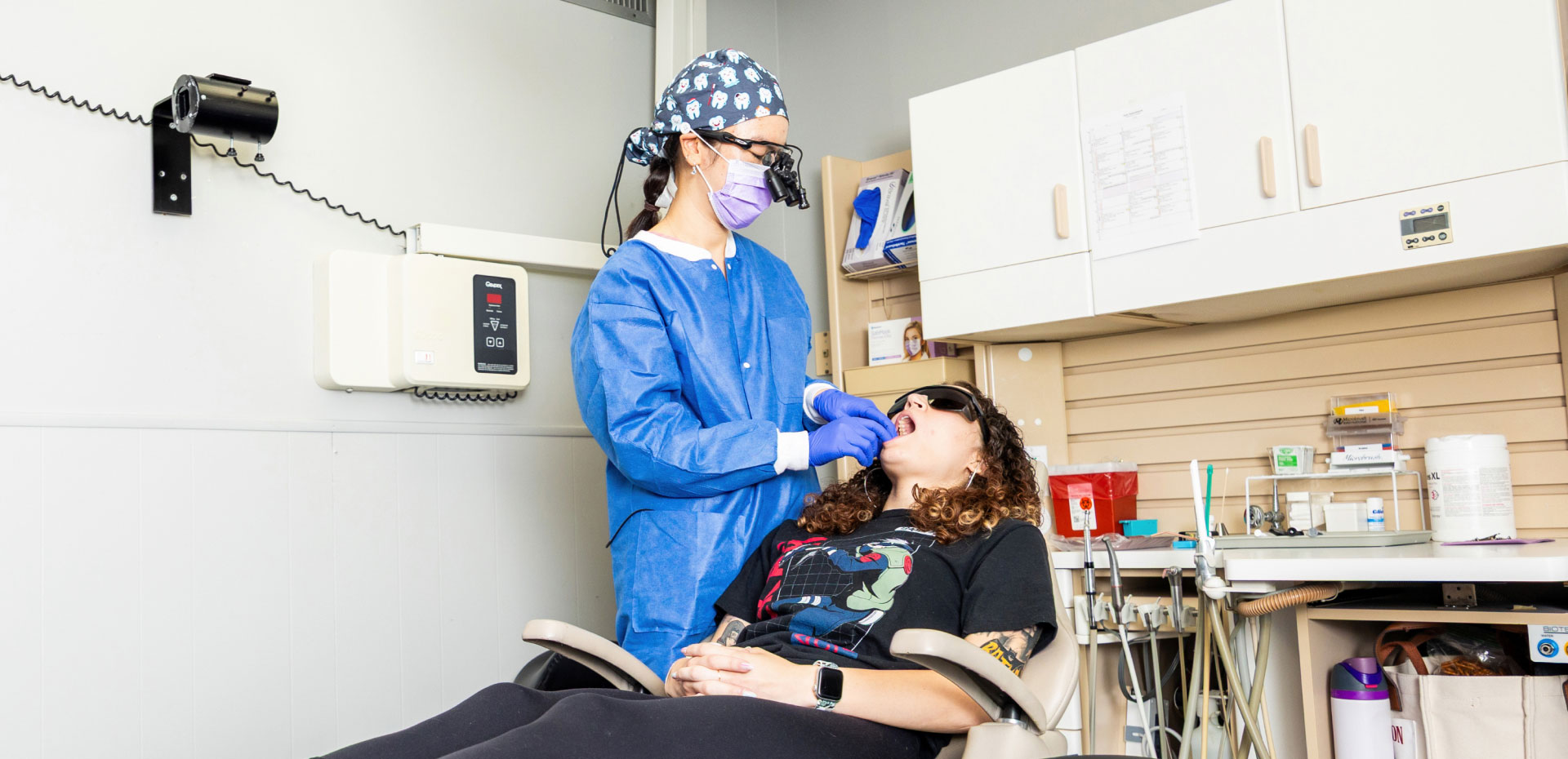 Dr. Nguyen performing dental exam on patient sitting in dental chair