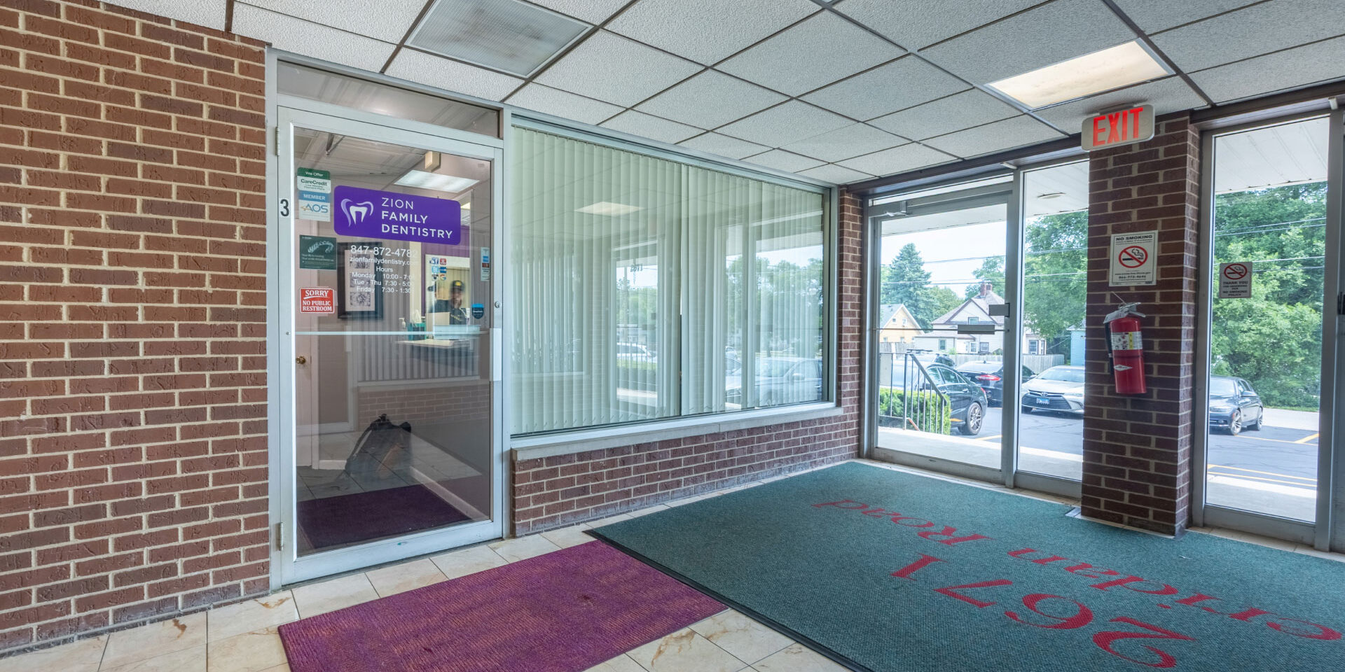 Zion Family Dentistry entrance inside on first floor of office building, brown brick wall, glass door